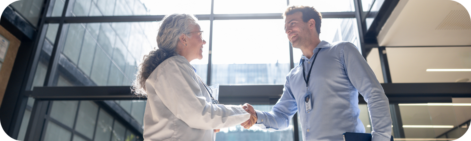 Two professionals shaking hands in a modern glass office